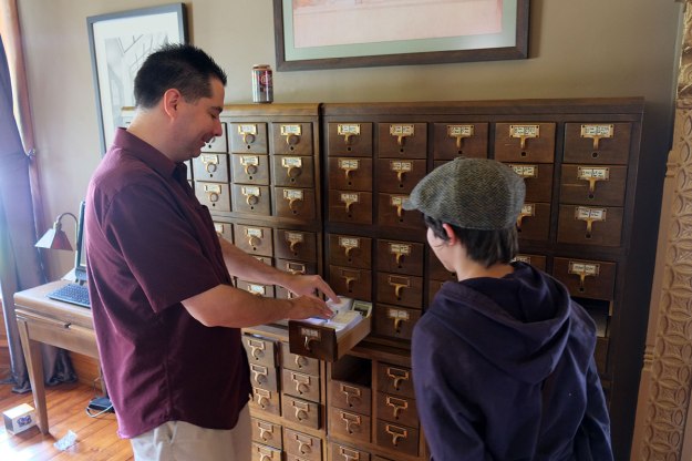 Aaron shows some of their stamp collection to Greta.
